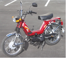 A red moped sitting on a paved driveway